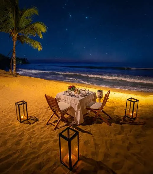 Table on a beach at night lit by lanterns under a starry sky